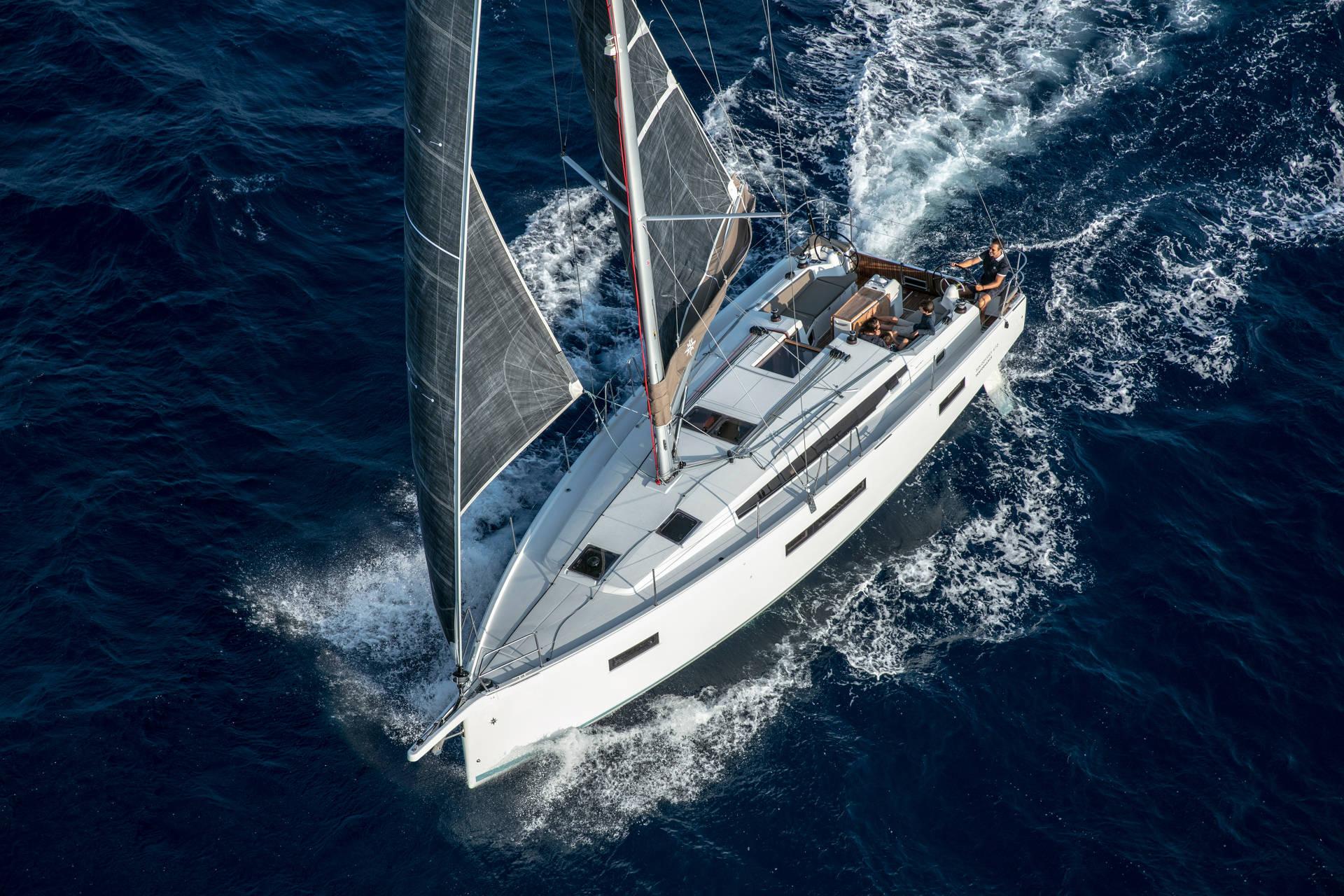 A Jeanneau under full sail in deep blue water, seen from above